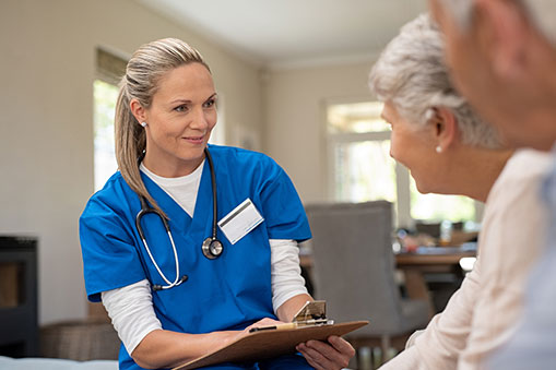 Blond Nurse With a Clip Board Listening to Elderly Patients