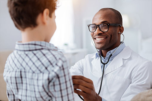 Photo of a Smiling Doctor Using His Stethoscope to Check a Child Patient